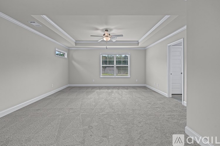 A spacious room with a ceiling fan and carpeted floor.