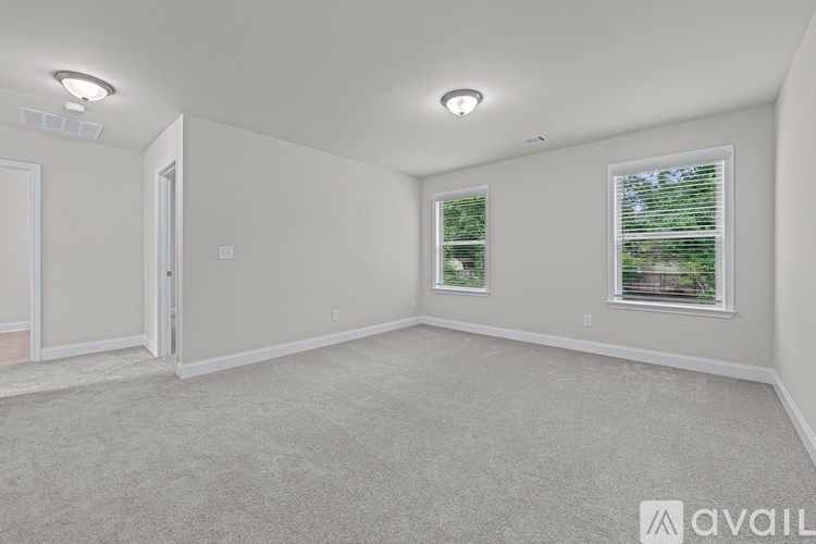 A room with a carpeted floor, two windows, and a door.