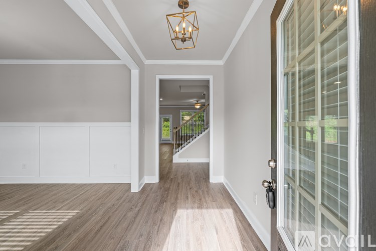 A hallway with a wooden floor and a glass door leading to a balcony.