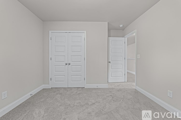 A room with a carpeted floor and two doors.