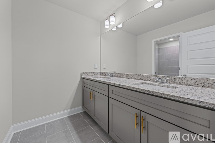 A bathroom with a marble countertop and grey cabinets.