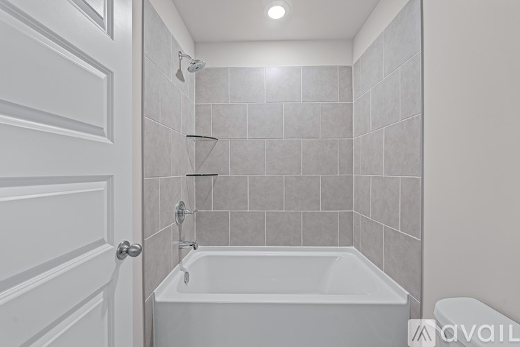 A white bathroom with a tub and a door.