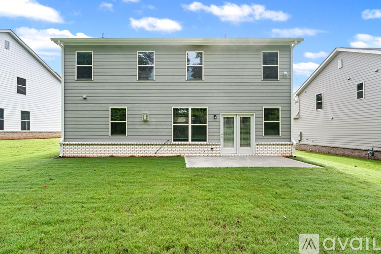 A two-story house with a grey exterior and a large front yard.