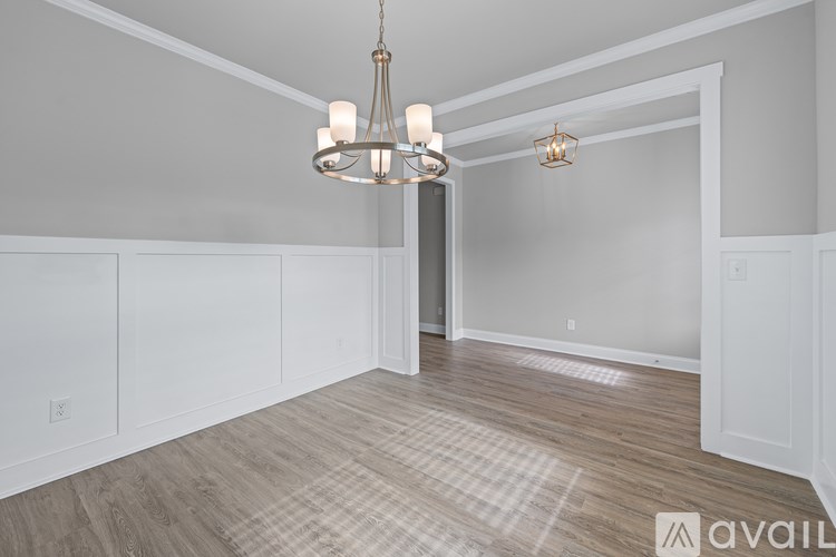A room with a wooden floor and a chandelier hanging from the ceiling.