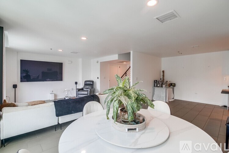 A white table with a plant on it in a room with a bed and a painting on the wall.