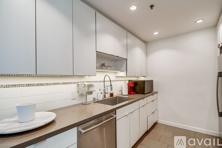 A modern kitchen with white cabinets and a stainless steel sink.