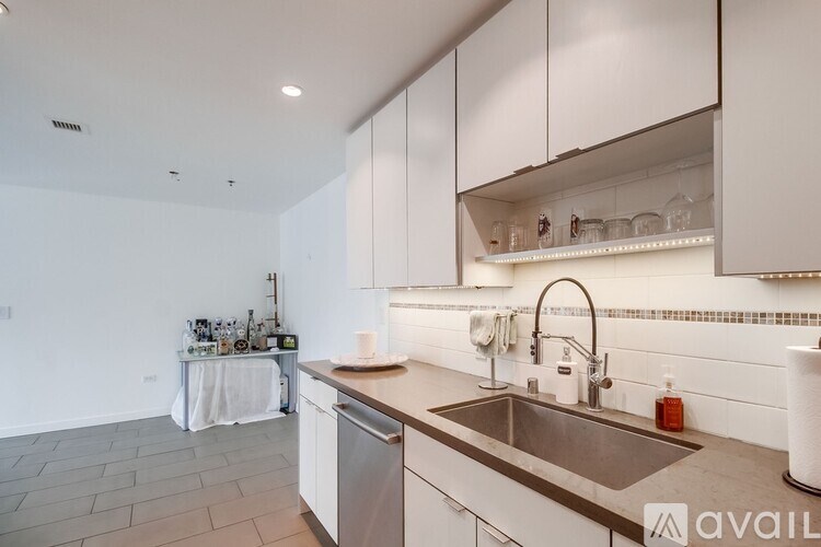 A modern kitchen with a stainless steel sink and white cabinets.