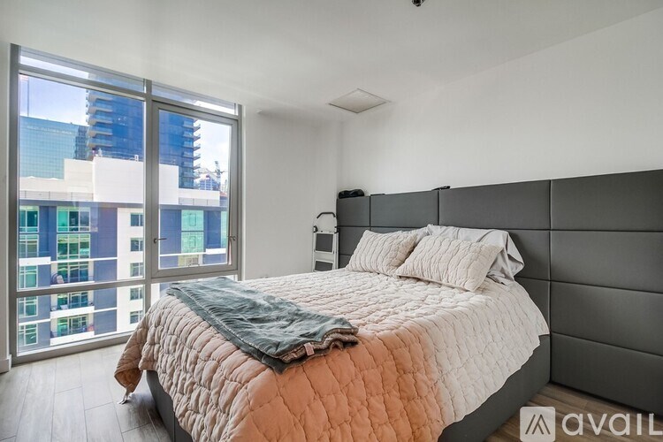 A bedroom with a large bed and a view of a cityscape through the window.