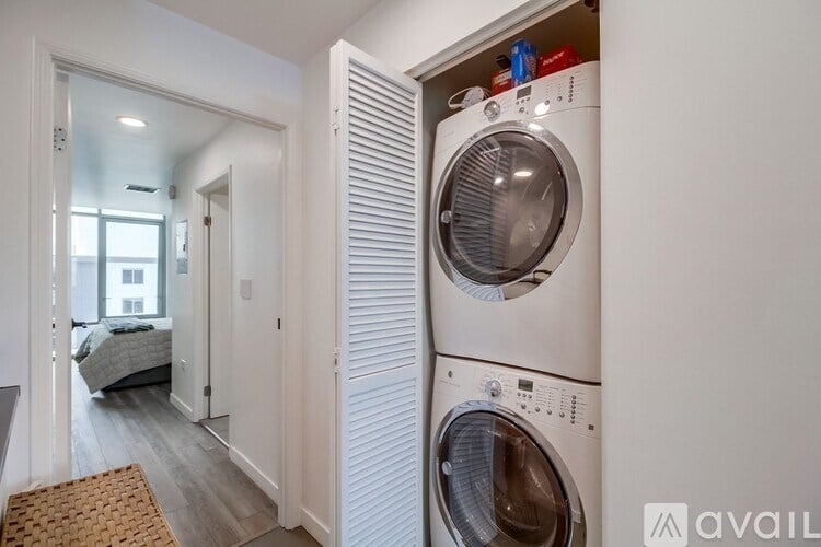 A washing machine is in a small room with a mat on the floor.