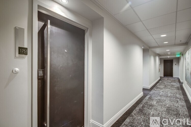 A hallway with a door on the left and a carpeted floor.