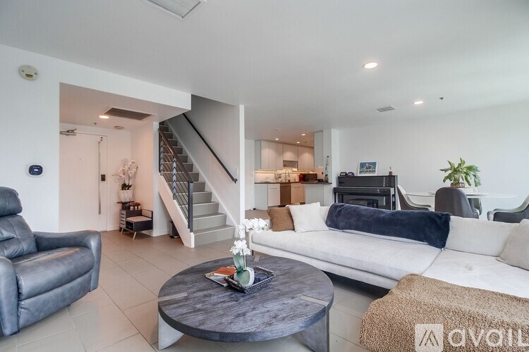 A living room with a couch, coffee table, and staircase.