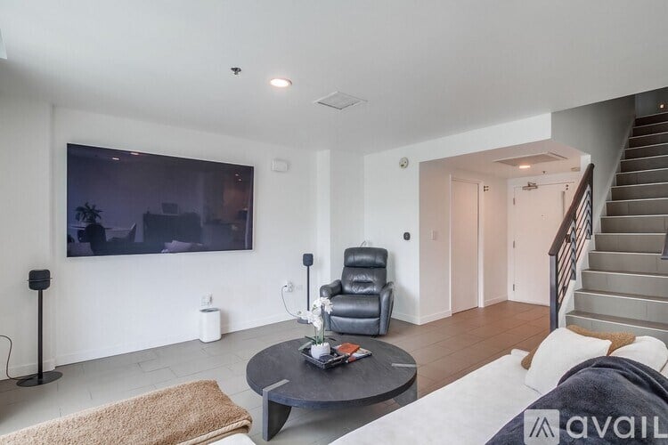 A living room with a black leather chair and a flat screen TV mounted on the wall.
