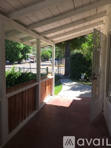 A patio with a white door and a white railing with a view of a street.