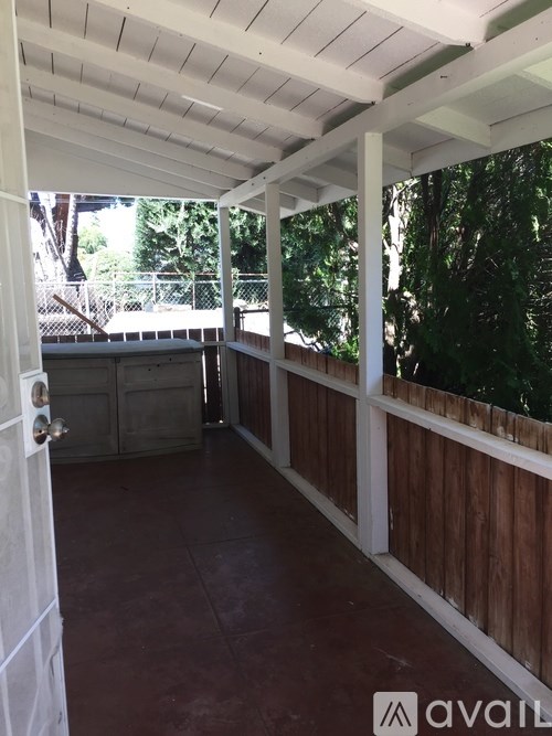 A covered patio with a white door and wooden railings.