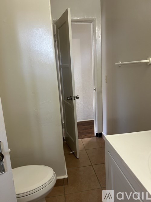 A white toilet in a small bathroom with a door open to a hallway.