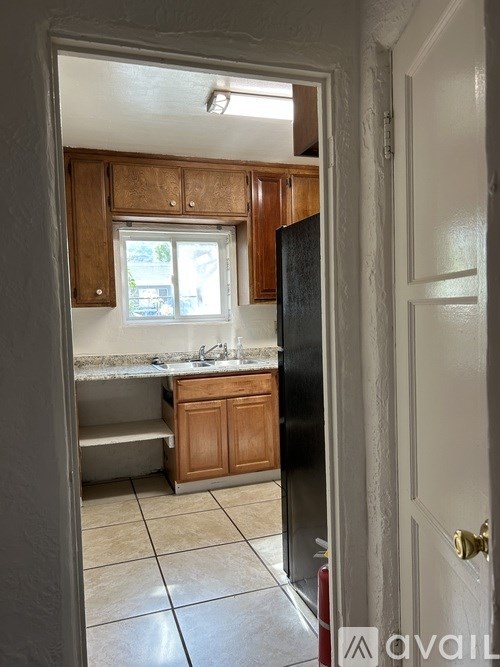A kitchen with wooden cabinets and a black refrigerator.