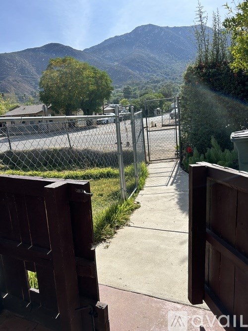 A view from behind a gate looking out to a road and mountains.