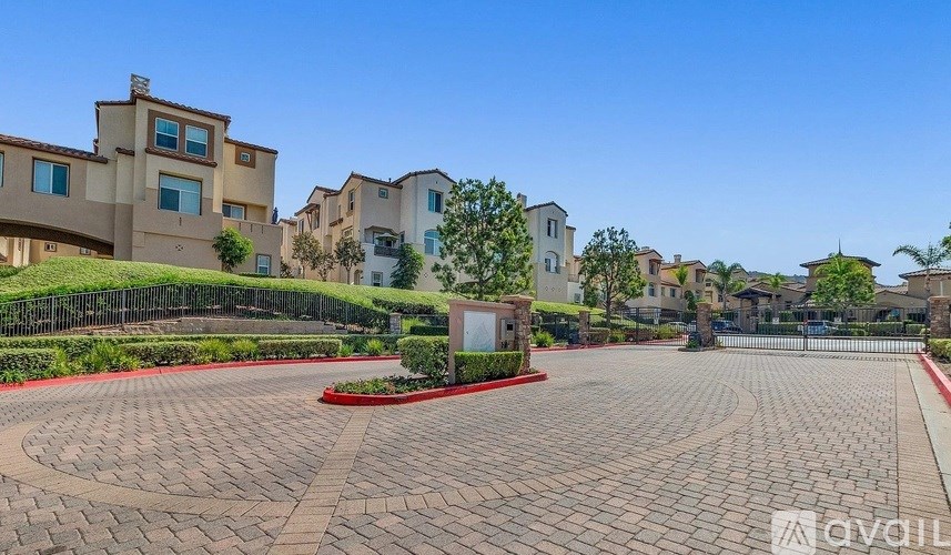 A residential area with a circular driveway and houses in the background.