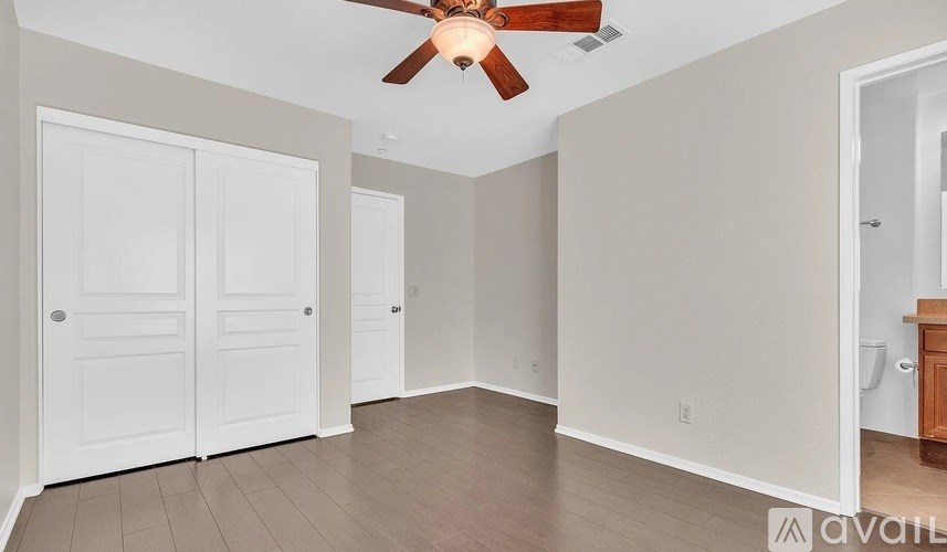 A room with a ceiling fan and two doors.