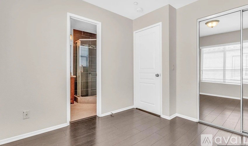 A room with a white door and a mirror on the wall.