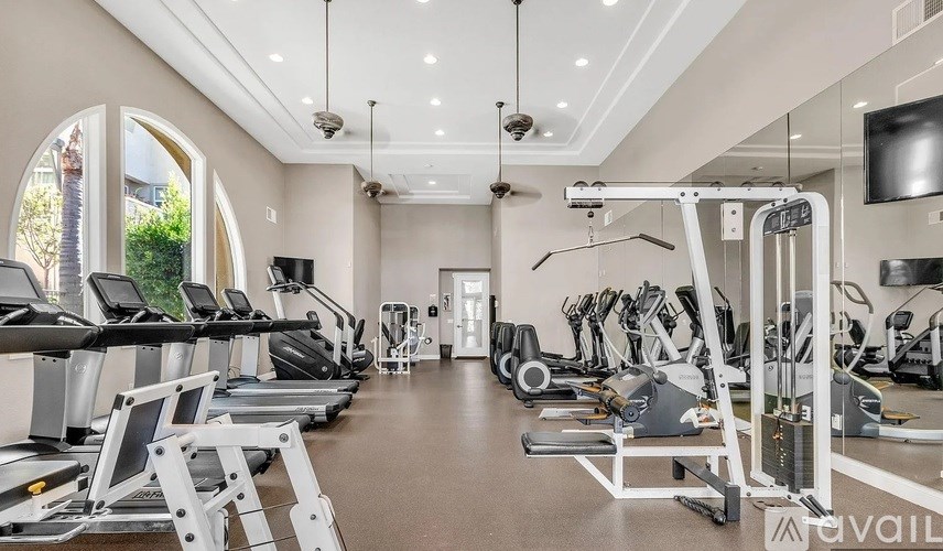 A spacious gym with a variety of equipment including treadmills, elliptical machines, and weight machines.