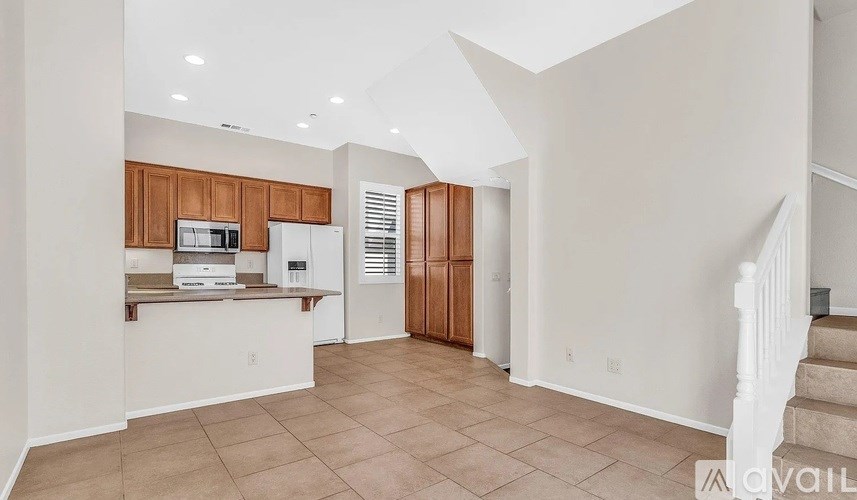 A kitchen with white walls and wooden cabinets.