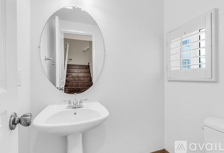 A white sink in a bathroom with a round mirror.
