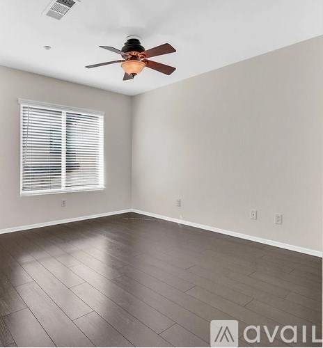A room with a ceiling fan and a window with blinds.