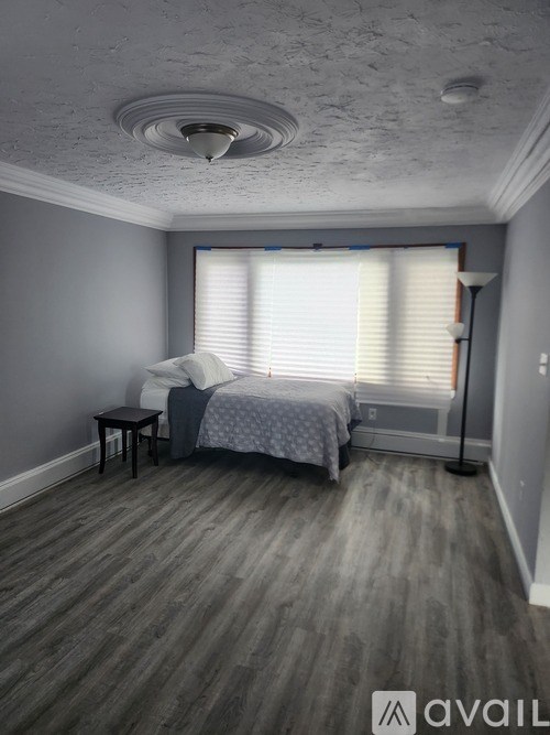 A bedroom with a bed, nightstand, and window with blinds.