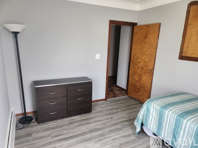 A bedroom with a bed, dresser, and a lamp.