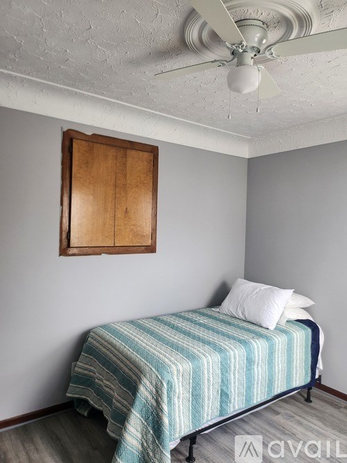 A bedroom with a bed, pillow, and a wooden picture frame on the wall.