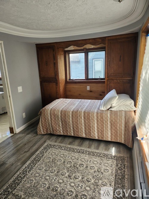 A bedroom with a bed, wooden headboard, and a patterned rug.