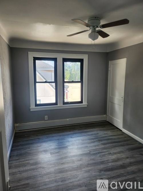 A room with a ceiling fan and two windows.