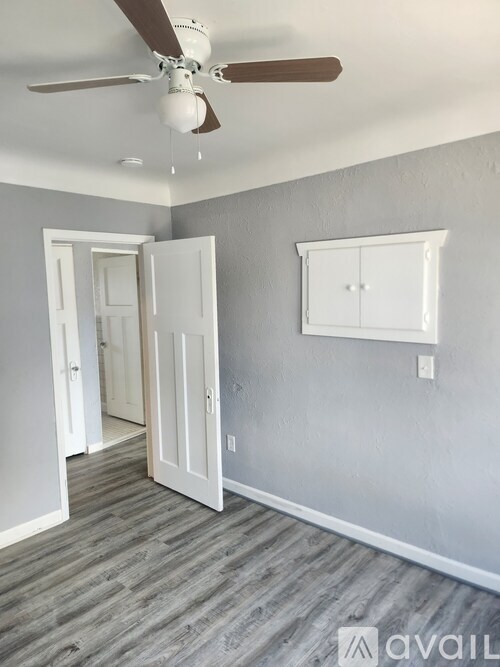 A room with a ceiling fan and a cabinet on the wall.