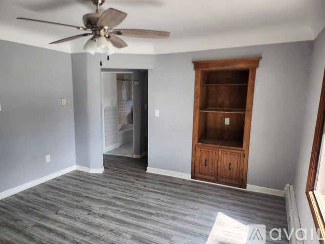 A room with a ceiling fan and a wooden cabinet.