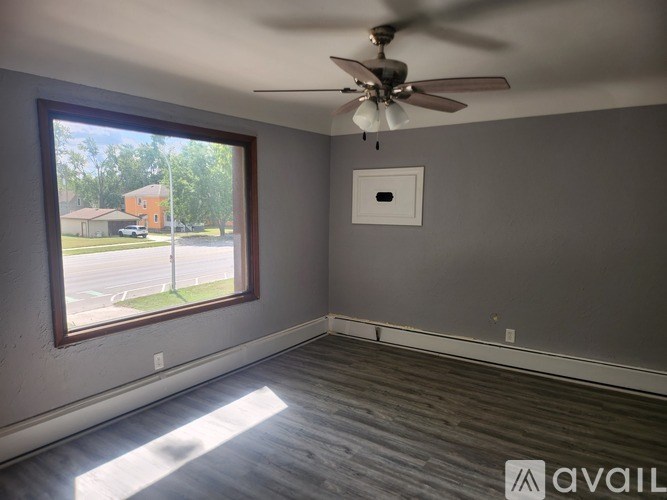 A room with a ceiling fan and a window overlooking a street.