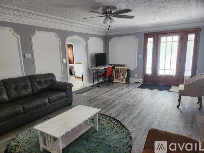 A living room with a black leather couch and a wooden coffee table.
