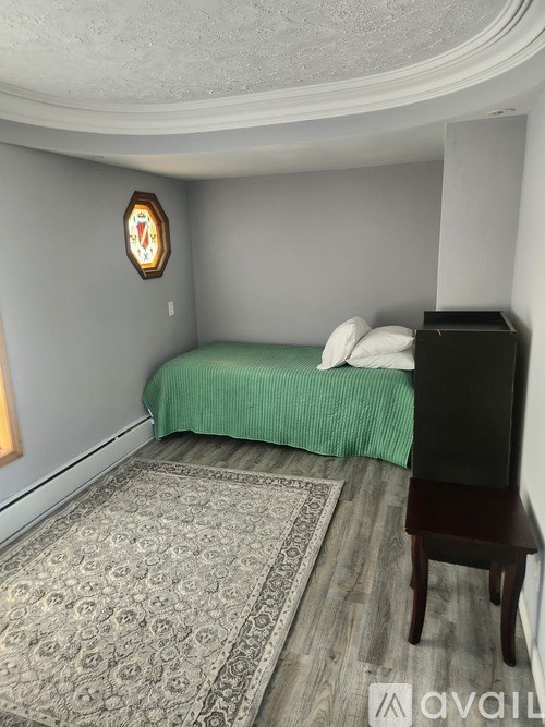 A bedroom with a bed, a chair, and a rug.