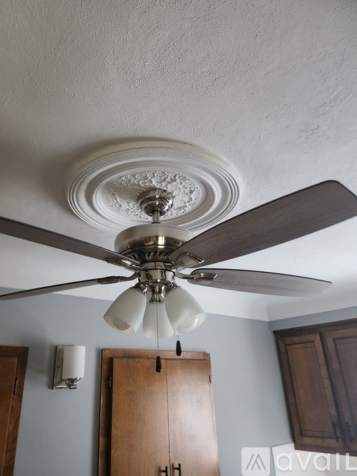 A ceiling fan with five blades and a light fixture hangs from the ceiling.
