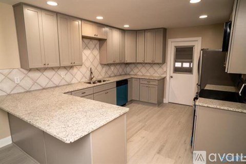 A kitchen with a granite counter top and white cabinets.