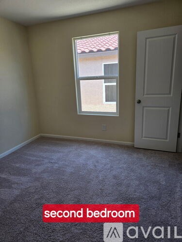 A second bedroom with a carpeted floor and a window.