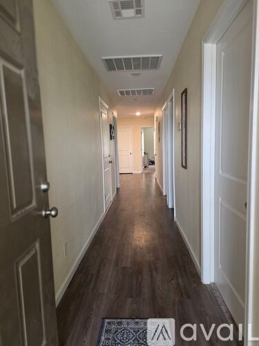 A hallway with wood floors and white walls.