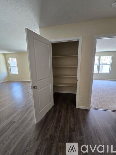 A room with a white door and wooden flooring.