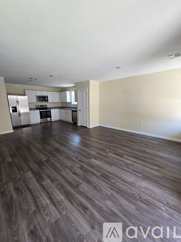 A spacious kitchen with white appliances and a wooden floor.
