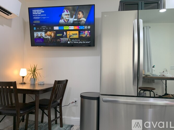 A modern kitchen with a TV mounted above the dining table.