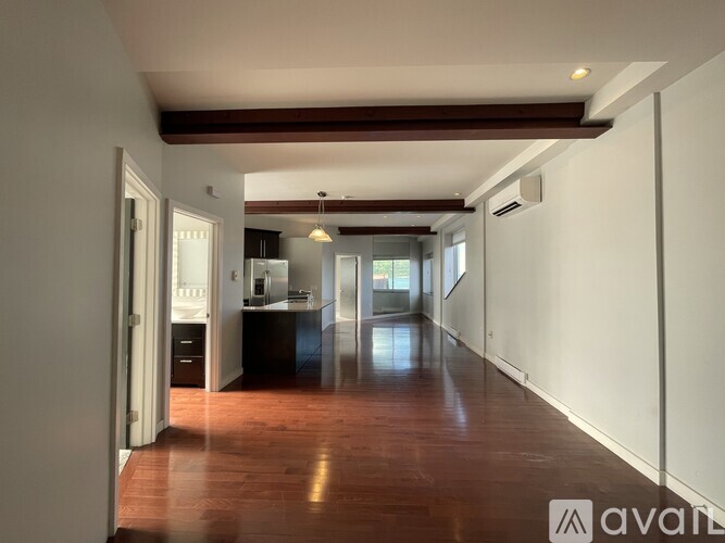 A kitchen with dark wood floors and white walls.