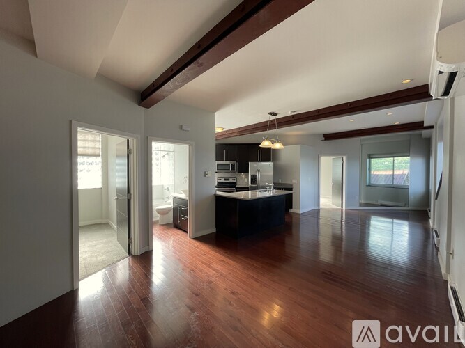 A spacious room with wooden floors and a staircase on the left side.