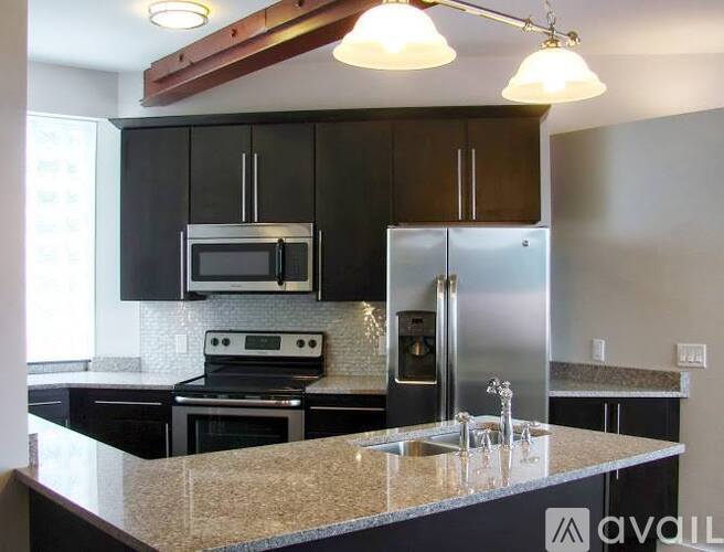 A kitchen with black cabinets and stainless steel appliances.