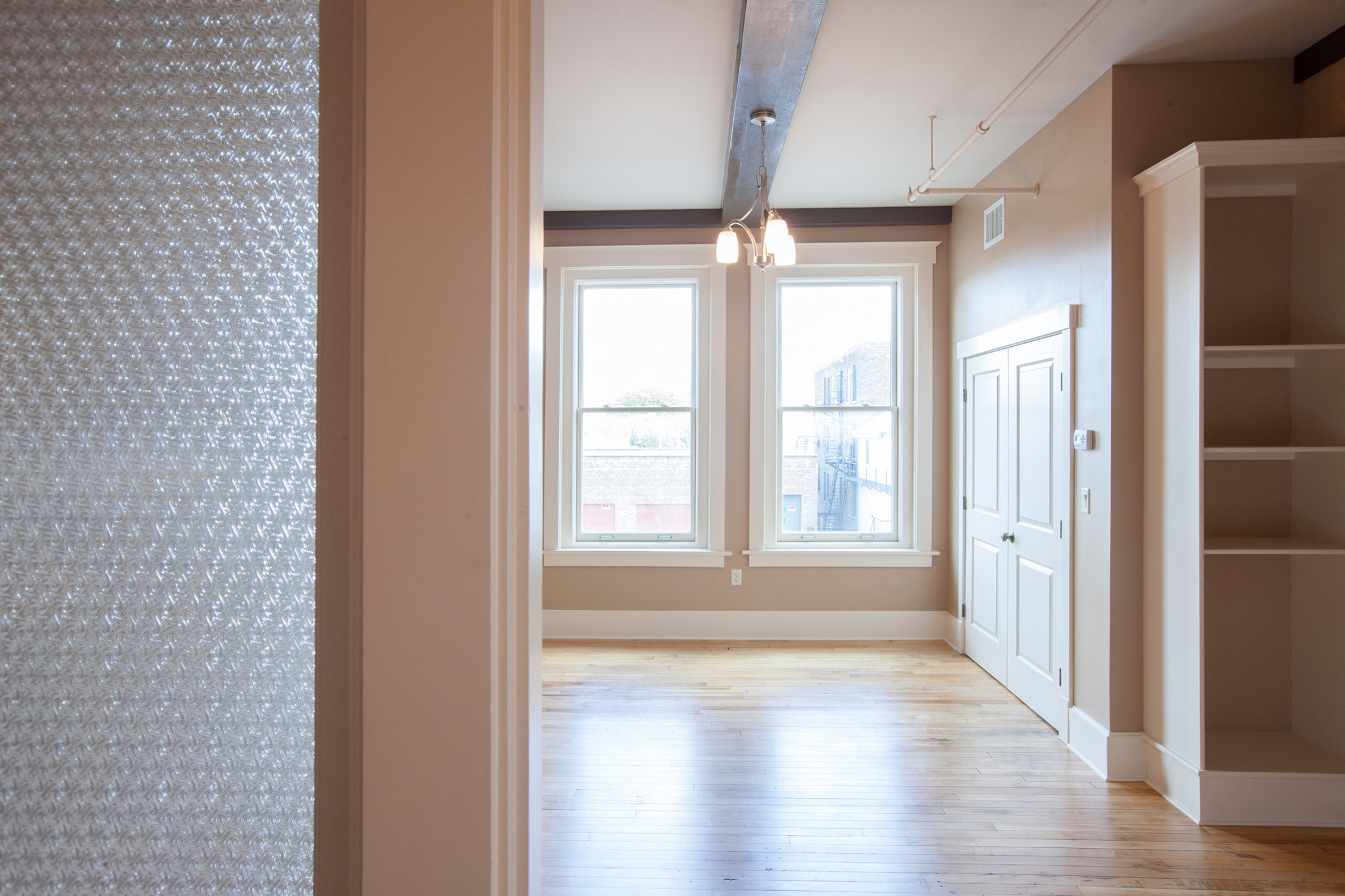 an empty living room with a wood floor and windows