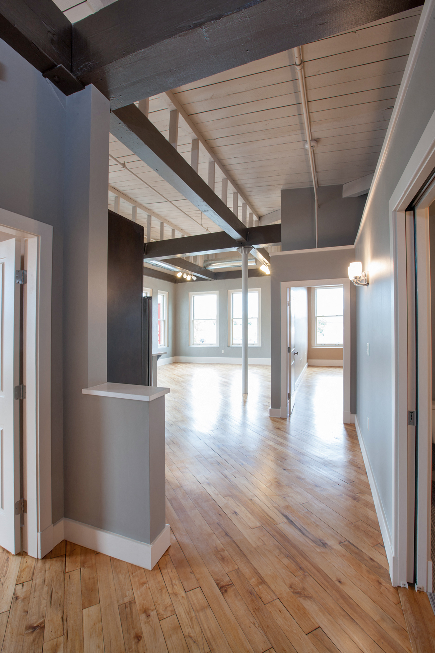 a living room with a hard wood floor and a ceiling with exposed beams